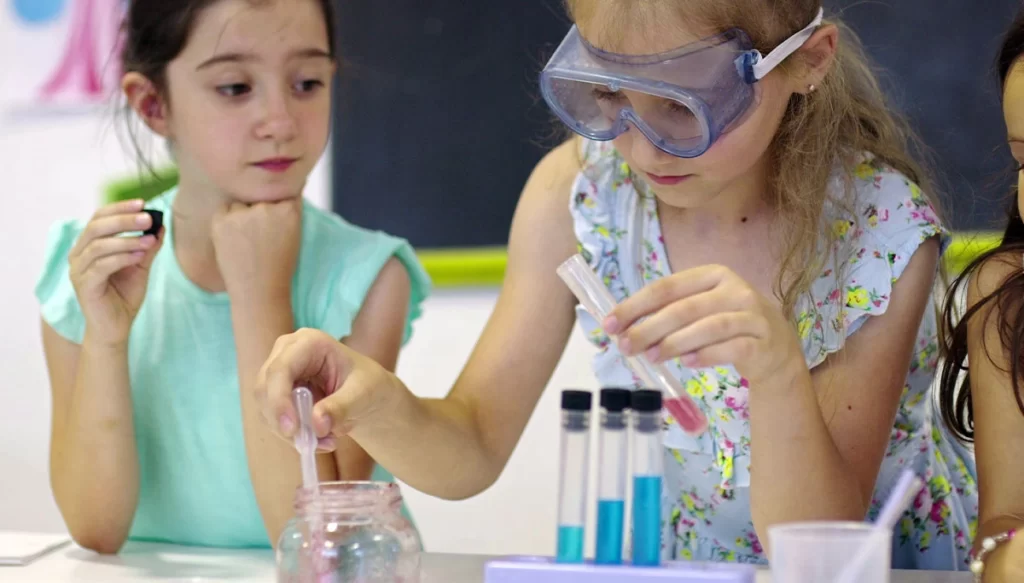 a young girl wears goggles while working with test tubes