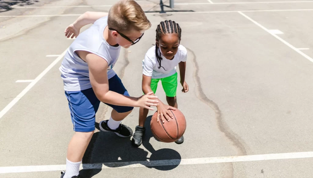 2 children playing basketball