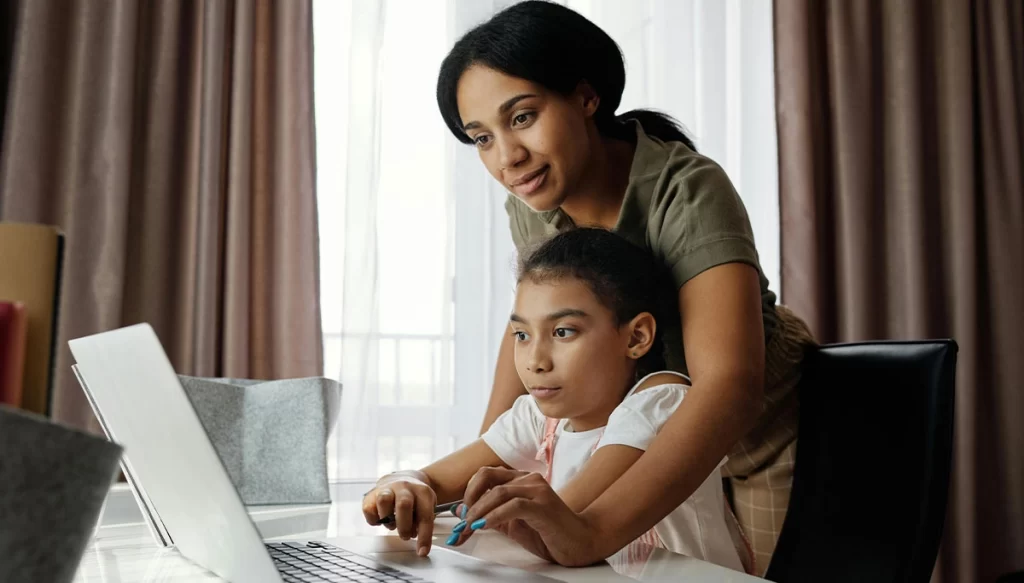 mother helping daughter on a laptop