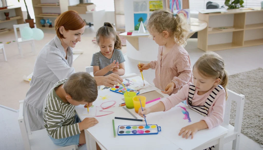 Adult Female at a table with other children using arts and crafts